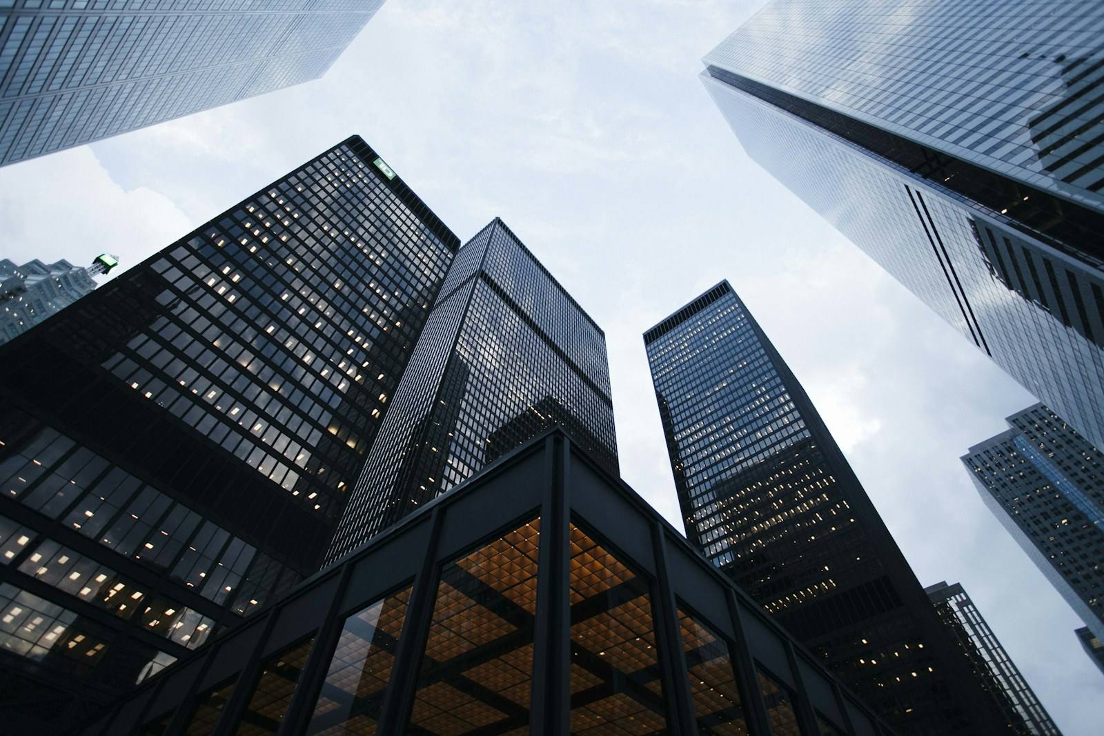 Tall glass office towers viewed from below against a pale sky